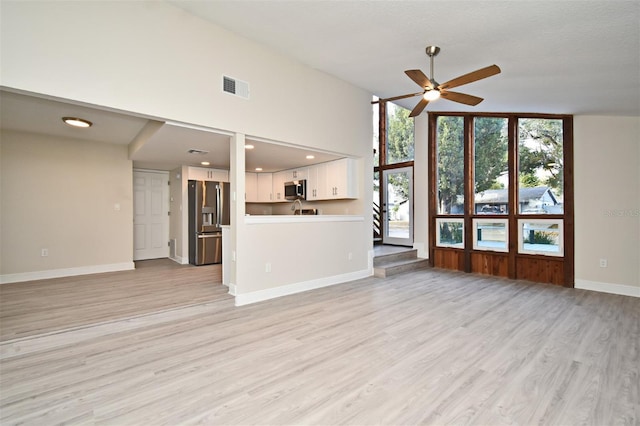 unfurnished living room with vaulted ceiling, ceiling fan, and light hardwood / wood-style floors