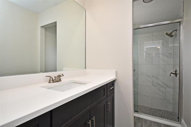 bathroom with a shower with shower door and vanity