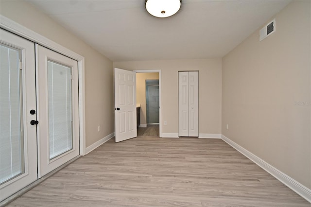 unfurnished bedroom featuring french doors and light hardwood / wood-style flooring