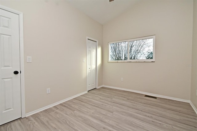 empty room with light hardwood / wood-style floors and vaulted ceiling