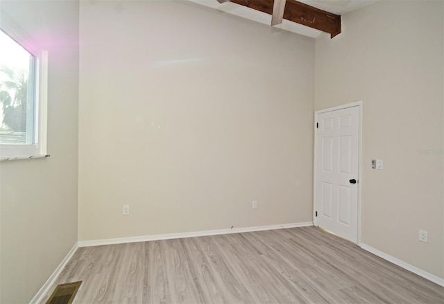 unfurnished room with beam ceiling and light hardwood / wood-style flooring