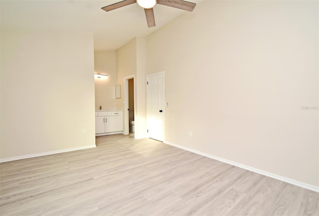 empty room with high vaulted ceiling, light hardwood / wood-style flooring, and ceiling fan