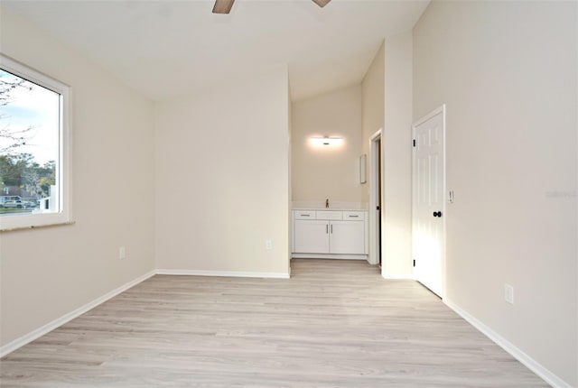 empty room with ceiling fan, lofted ceiling, and light wood-type flooring