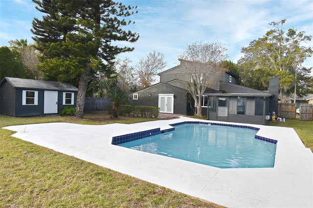 view of swimming pool featuring a lawn and a storage shed