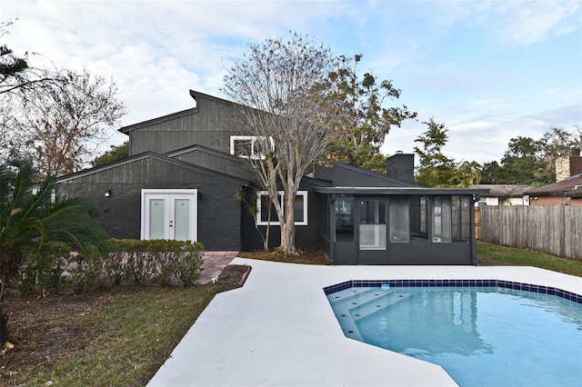 back of property with a fenced in pool and a sunroom