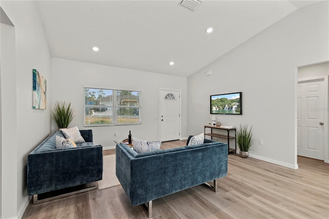 living room featuring lofted ceiling and light hardwood / wood-style floors