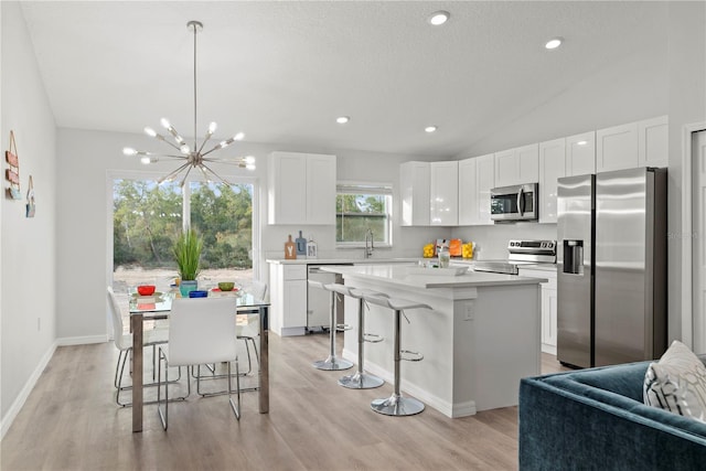 kitchen with stainless steel appliances, white cabinets, hanging light fixtures, and a kitchen island