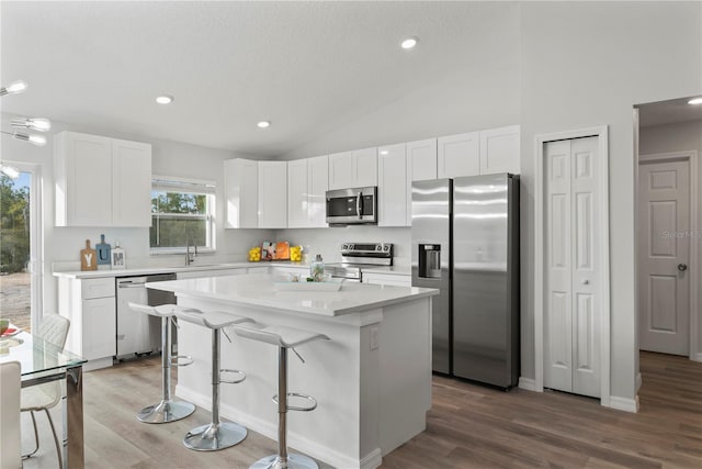 kitchen featuring stainless steel appliances, white cabinets, a kitchen island, and sink