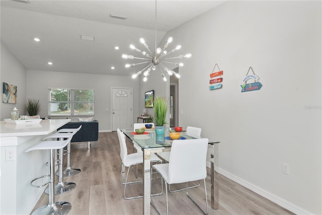 dining area featuring a textured ceiling, vaulted ceiling, a chandelier, and light wood-type flooring