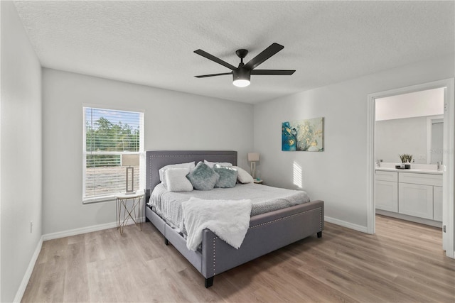 bedroom featuring ceiling fan, light hardwood / wood-style floors, a textured ceiling, and ensuite bath