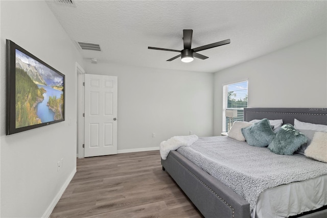 bedroom with a textured ceiling, ceiling fan, and wood-type flooring