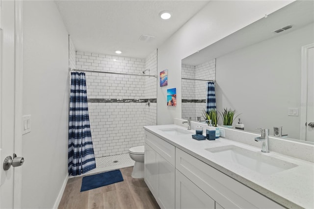 bathroom with toilet, wood-type flooring, walk in shower, a textured ceiling, and vanity