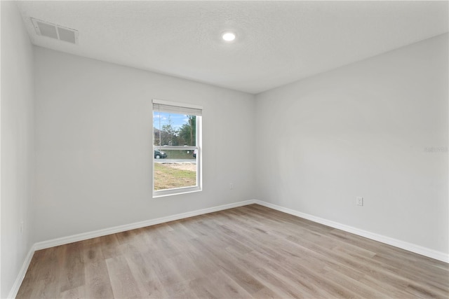 unfurnished room with a textured ceiling and light hardwood / wood-style flooring