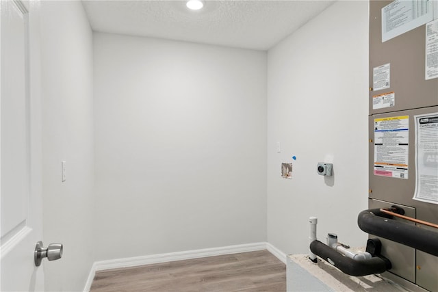 clothes washing area featuring a textured ceiling, washer hookup, light hardwood / wood-style flooring, and electric dryer hookup