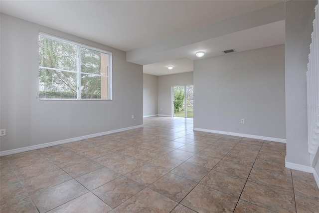 tiled spare room featuring a healthy amount of sunlight