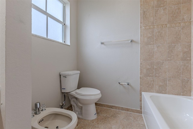 bathroom with a bidet, toilet, and a tub to relax in