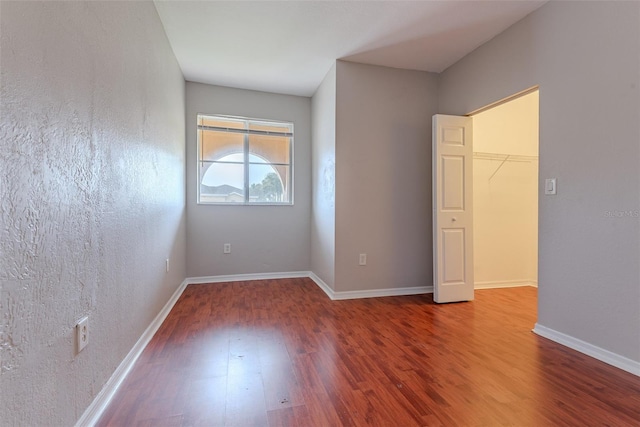 unfurnished bedroom featuring hardwood / wood-style flooring, a closet, and a spacious closet