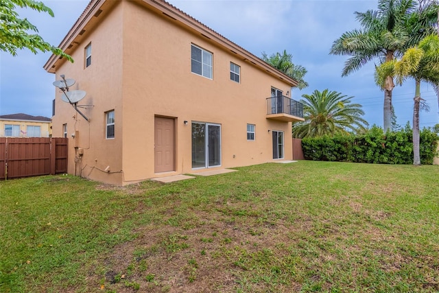 back of house with a balcony and a yard