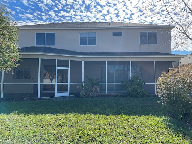 rear view of house with a sunroom and a lawn