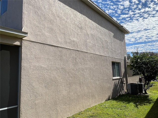 view of side of home featuring cooling unit and a lawn