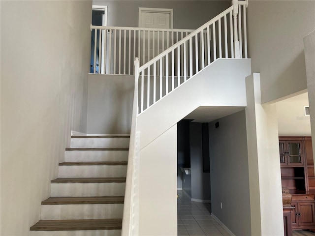 stairs with a towering ceiling and tile patterned flooring