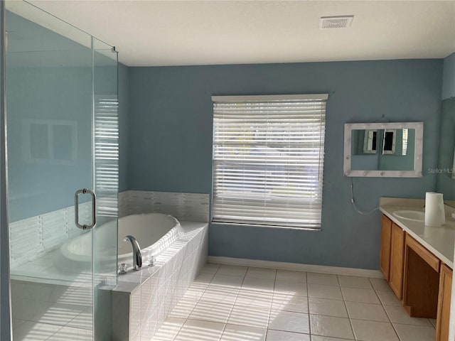 bathroom featuring vanity, a relaxing tiled tub, and tile patterned floors