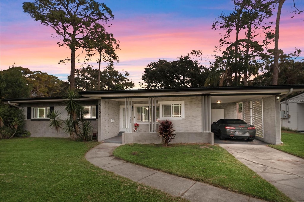 single story home featuring a lawn and a carport