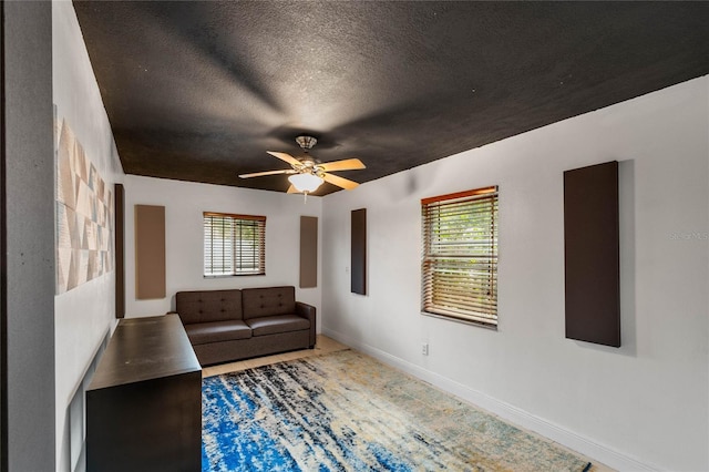 unfurnished living room with ceiling fan and a textured ceiling