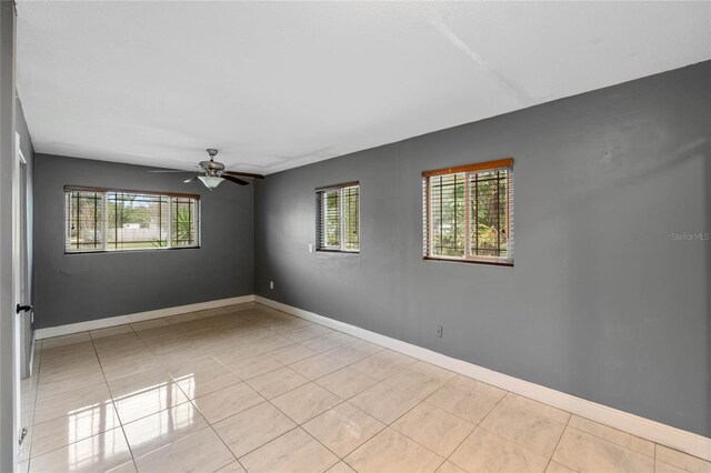 tiled empty room featuring ceiling fan and a wealth of natural light