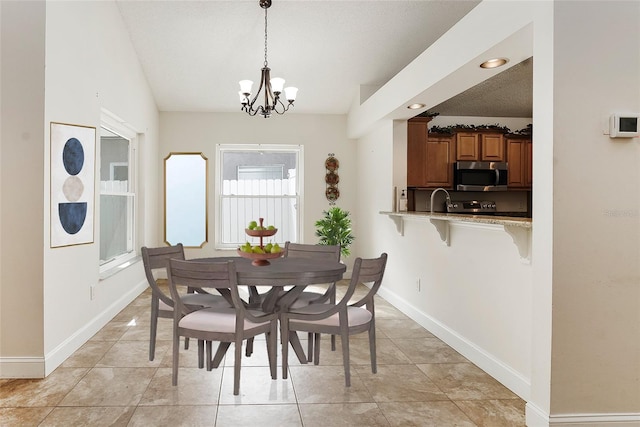 dining room featuring an inviting chandelier, light tile patterned floors, lofted ceiling, and sink