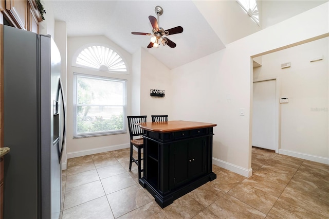 kitchen with stainless steel fridge with ice dispenser, ceiling fan, a kitchen breakfast bar, vaulted ceiling, and a center island