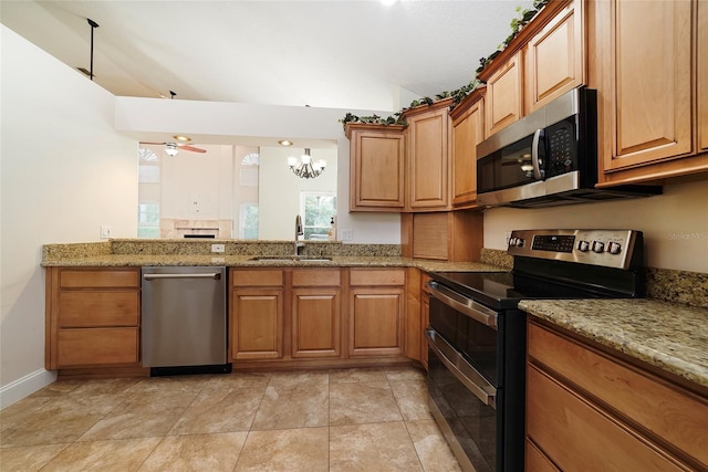 kitchen featuring ceiling fan with notable chandelier, light stone countertops, pendant lighting, appliances with stainless steel finishes, and sink