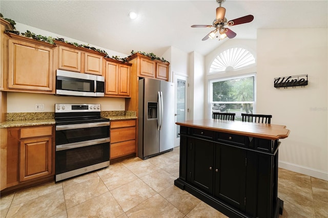 kitchen featuring light tile patterned floors, ceiling fan, appliances with stainless steel finishes, vaulted ceiling, and light stone counters