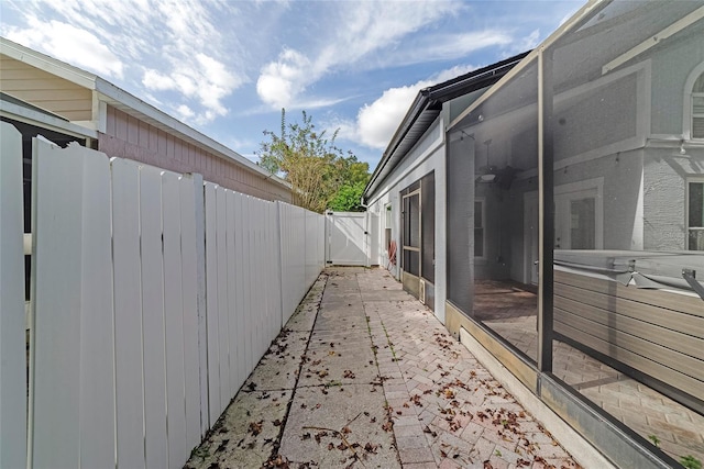 view of side of home featuring glass enclosure and a patio