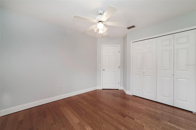 unfurnished bedroom featuring a textured ceiling, ceiling fan, dark hardwood / wood-style flooring, and a closet