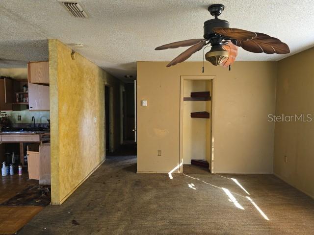 spare room with ceiling fan, dark carpet, and a textured ceiling