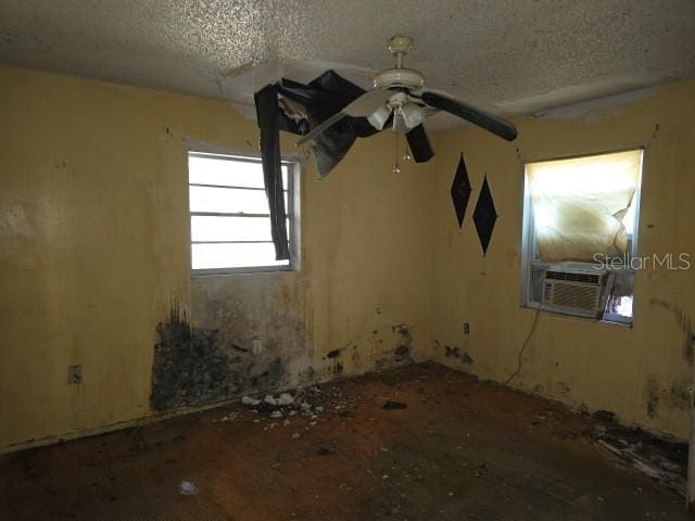 unfurnished room featuring ceiling fan, cooling unit, and a textured ceiling