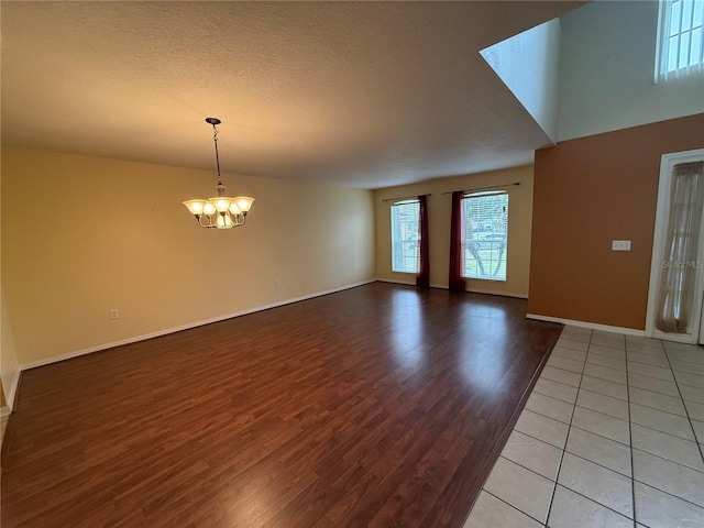 spare room with wood-type flooring, a textured ceiling, and a chandelier