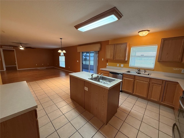 kitchen featuring sink, hanging light fixtures, an island with sink, and light tile patterned floors