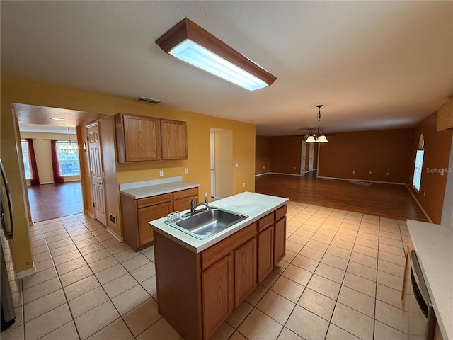 kitchen with a kitchen island with sink, sink, light tile patterned floors, and decorative light fixtures