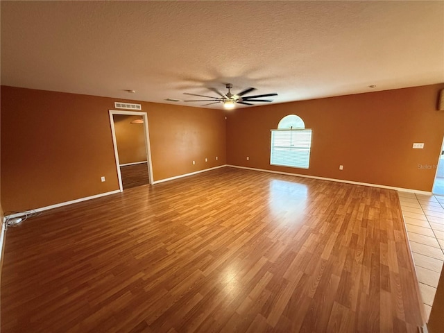 empty room featuring hardwood / wood-style flooring, ceiling fan, and a textured ceiling