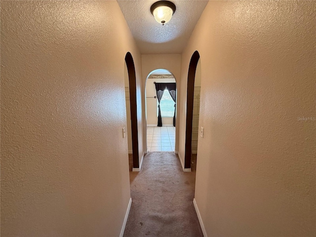 hall featuring a textured ceiling and carpet