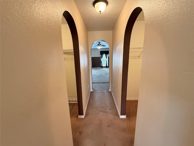 corridor featuring a textured ceiling and carpet flooring