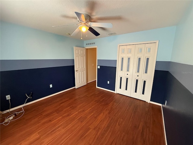 unfurnished bedroom with ceiling fan, dark hardwood / wood-style flooring, and a closet