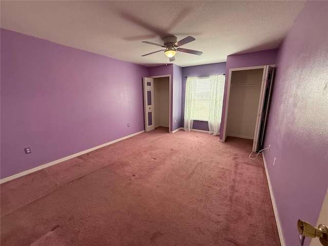 unfurnished bedroom with multiple closets, ceiling fan, light carpet, and a textured ceiling