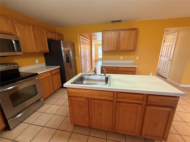 kitchen featuring a kitchen island with sink, sink, stainless steel appliances, and light tile patterned flooring