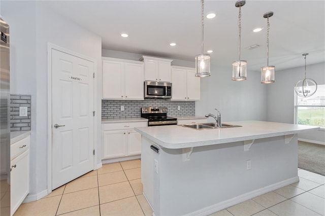 kitchen with appliances with stainless steel finishes, sink, a center island with sink, and white cabinets