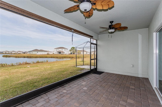 unfurnished sunroom with a water view and ceiling fan