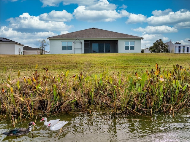 rear view of property featuring a water view and a yard