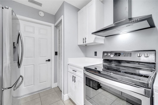 kitchen featuring white cabinetry, appliances with stainless steel finishes, wall chimney exhaust hood, and light tile patterned flooring